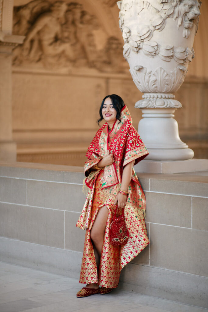 A person in colorful wedding attire leaning up against a banister 