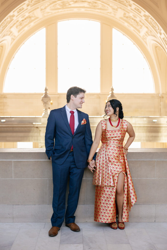 A newlywed couple holding hands and looking lovely at each other 