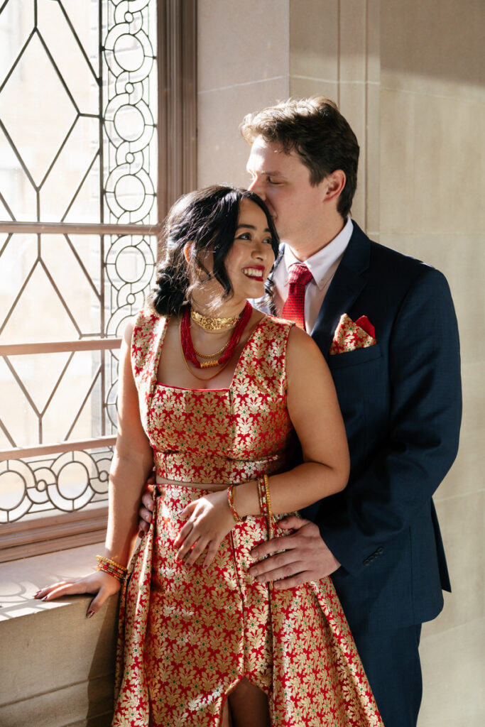 A person standing behind their partner and kissing their head 