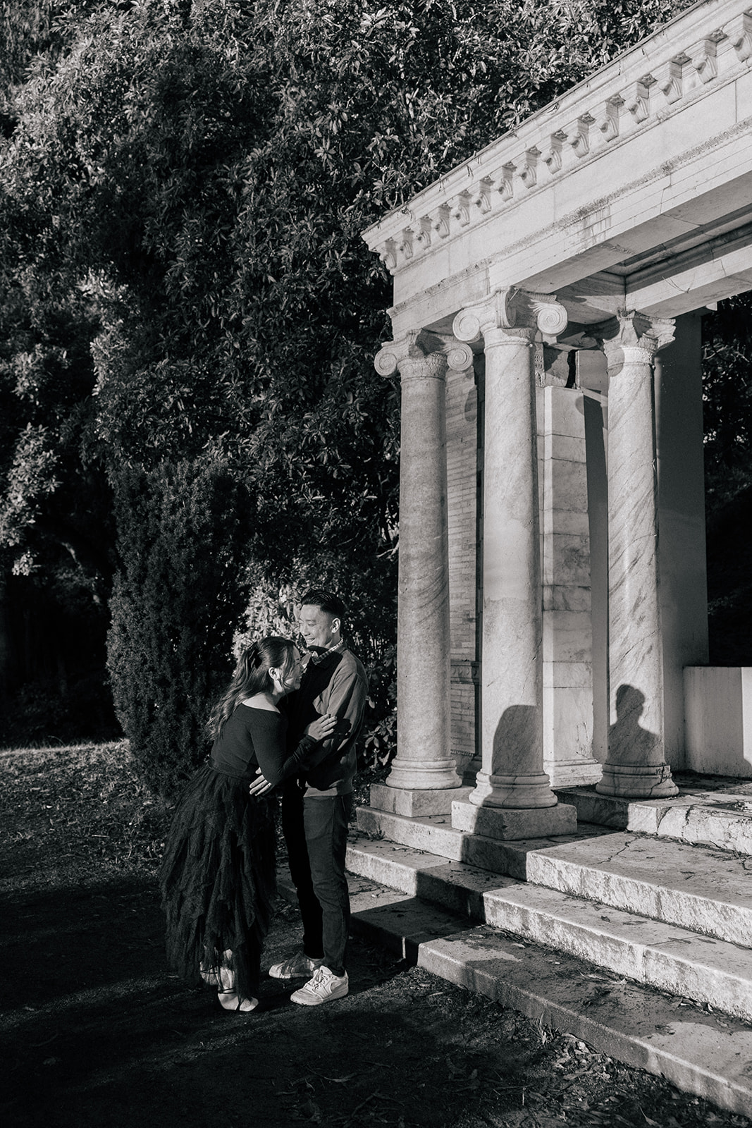 A couple embracing next to a marble column in a park