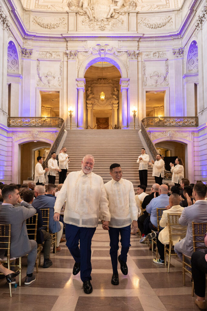 Newlyweds holding hands and walking back up the aisle after their wedding 