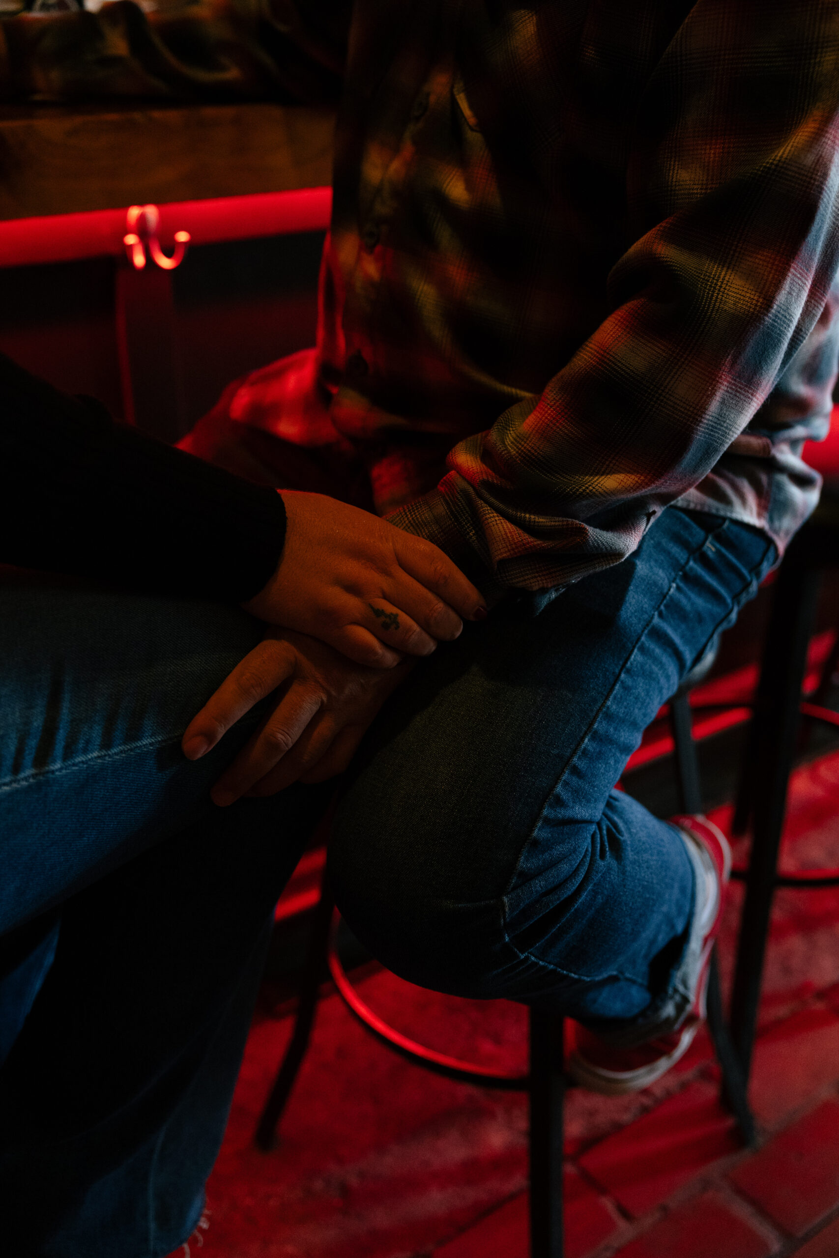 a couple sitting on a barstool and holding hands