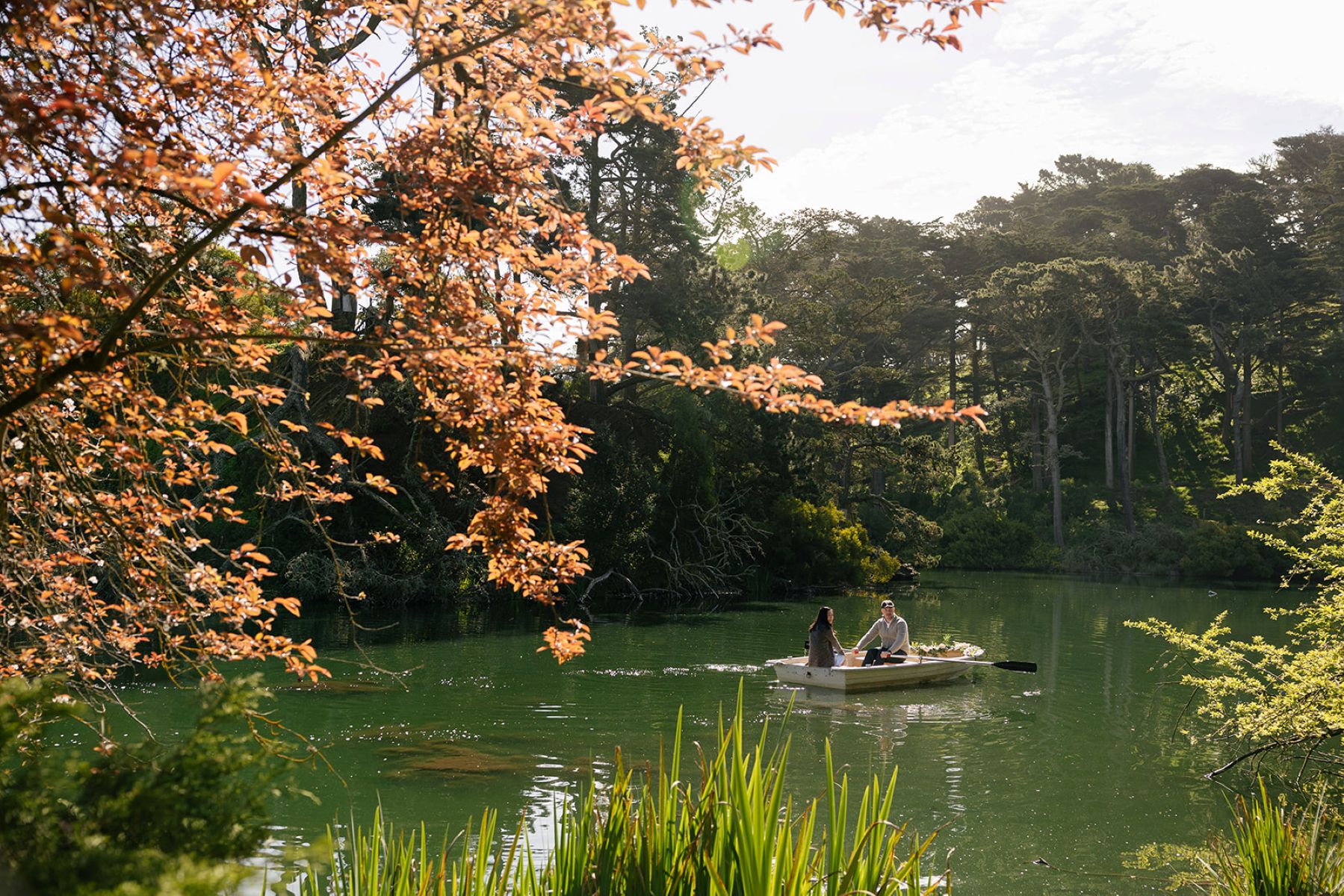 a couple in a row boat taking engagement pictures at blue heron boathouse on stow lake