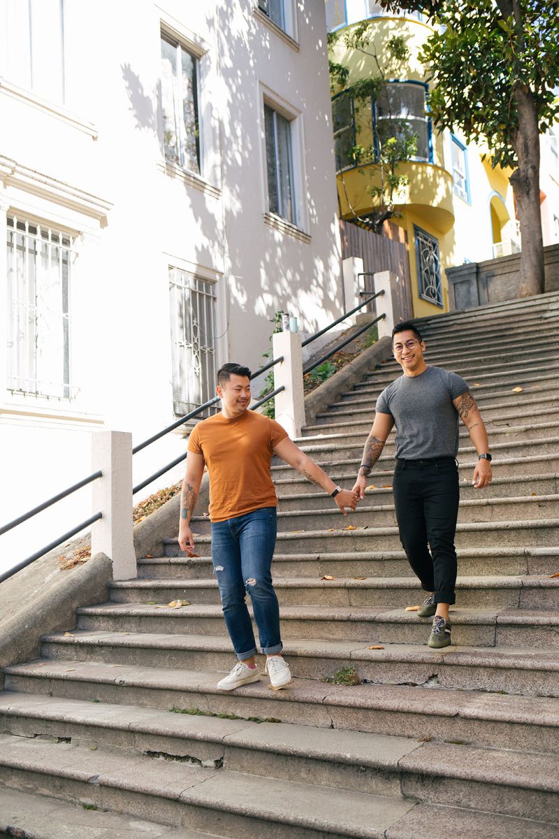 a couple taking engagement pictures in downtown san francisco holding hands and walking down steps together