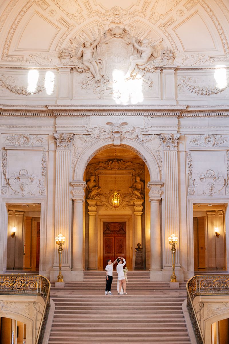 a couple spinning each other in san francisco city hall during their engagement photo session