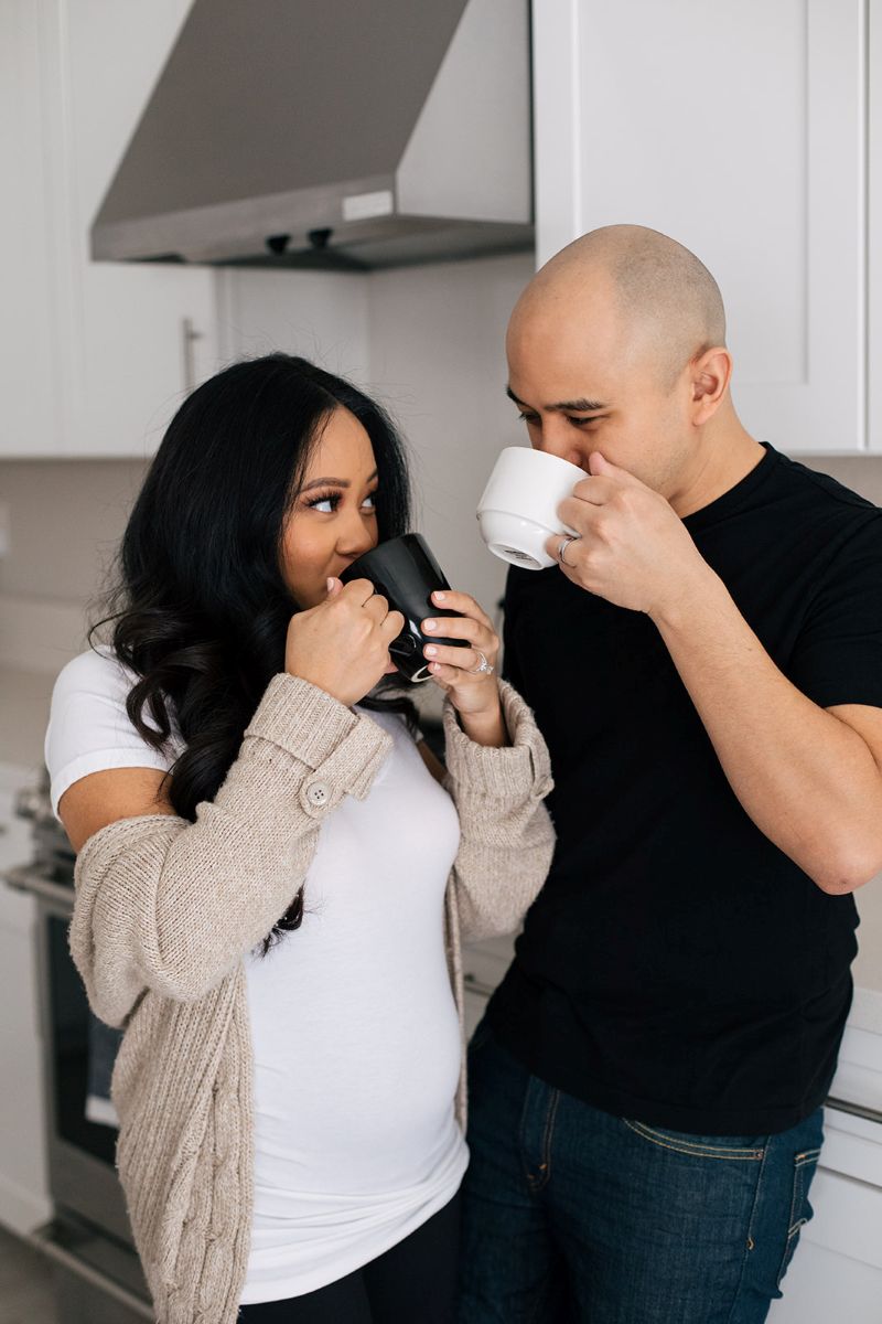 a couple having a lifestyle engagment session in their home they are both drinking coffee and looking at each other