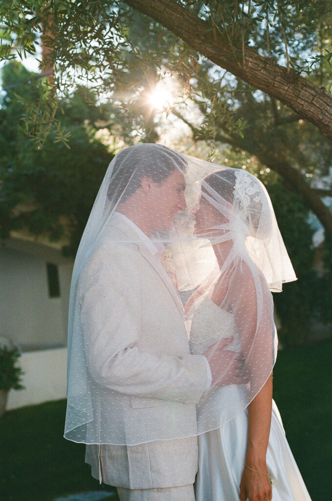 a wedding couple facing one another under a veil