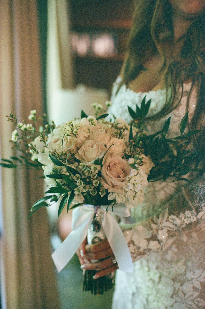 film wedding photography a bride is holding a bouquet of flowers in her hand wrapped with a white ribbon 