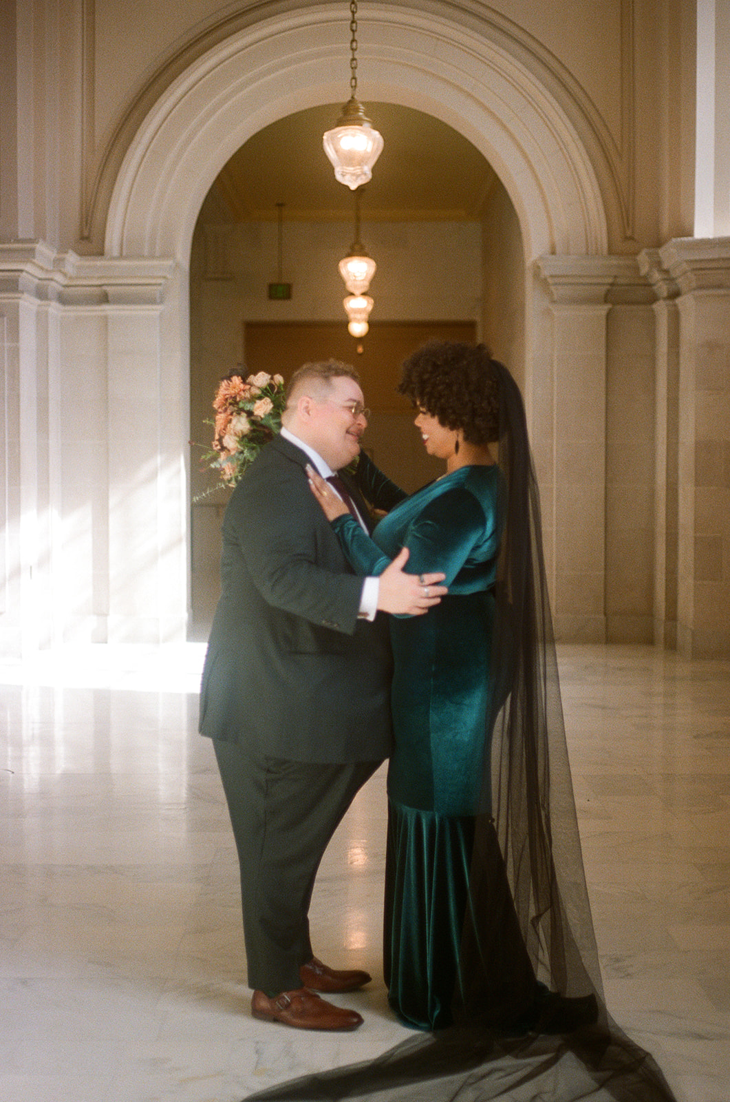 a couple embracing each other in san francisco city hall on the day of their wedding 