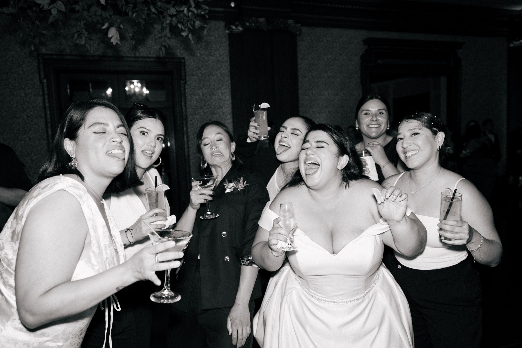 a woman smiling and dancing with her friends at her wedding reception 