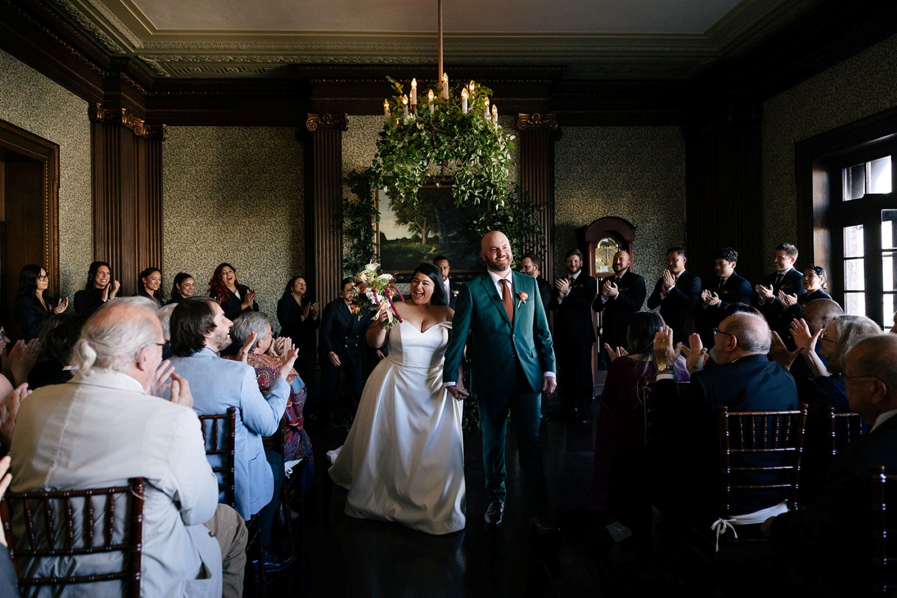 a couple holding hands and smiling with their guests after their wedding ceremony at the University Club of San Francisco