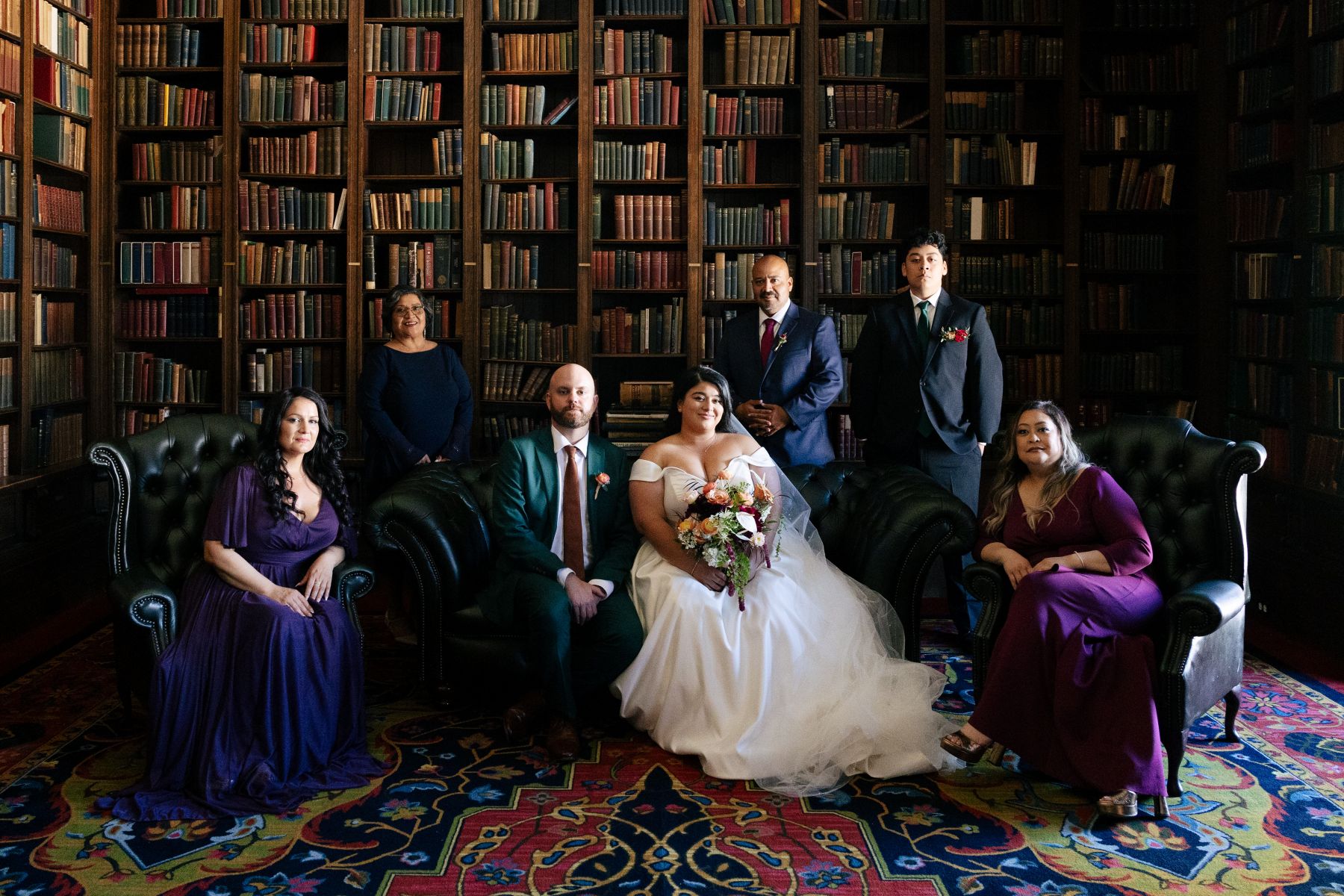 a couple taking wedding portraits with their family in the library of the University Club of San Francisco