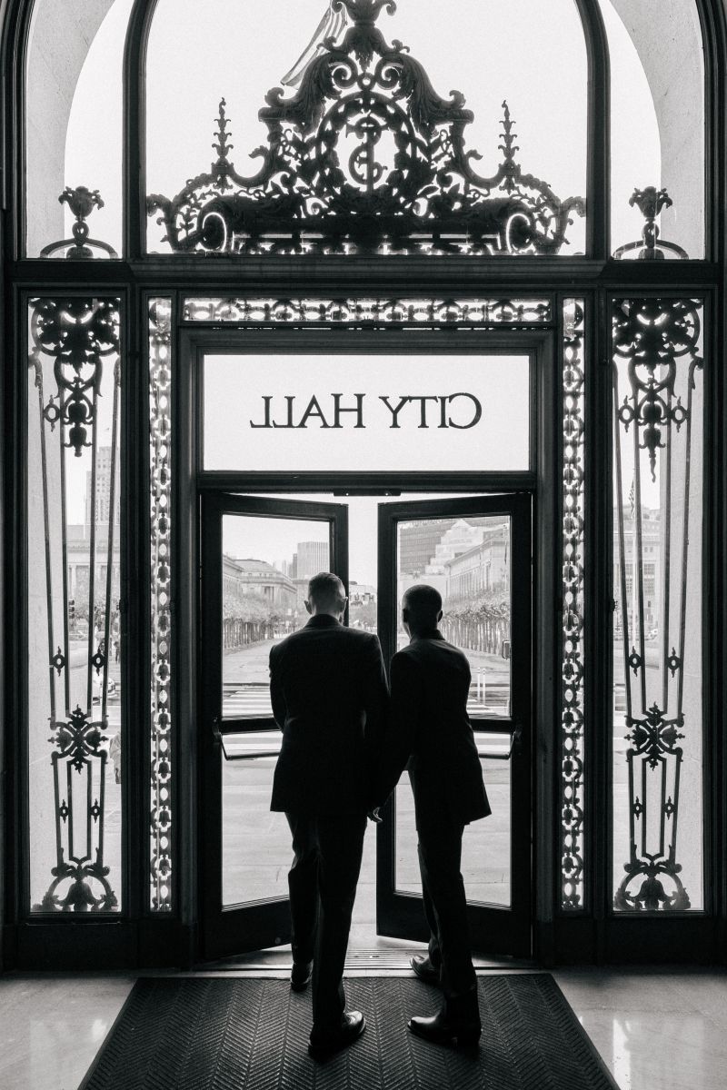a couple walking out of san francisco city hall on the day of their wedding holding hands