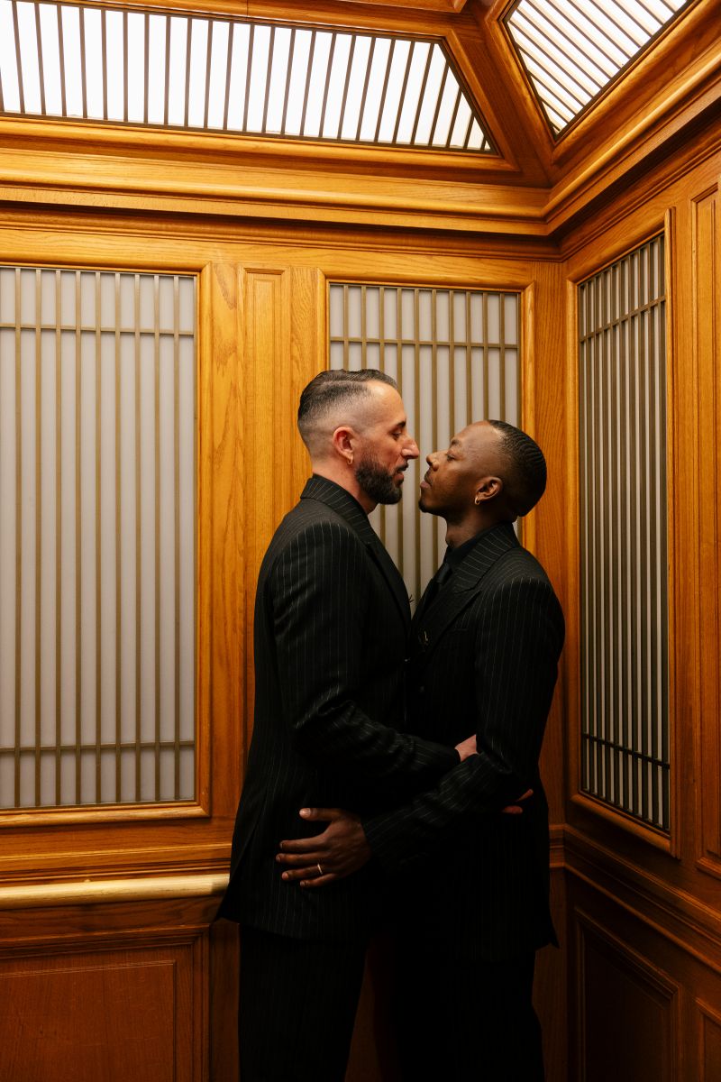 a couple wearing matching black suits embracing each other inside of san francisco city hall