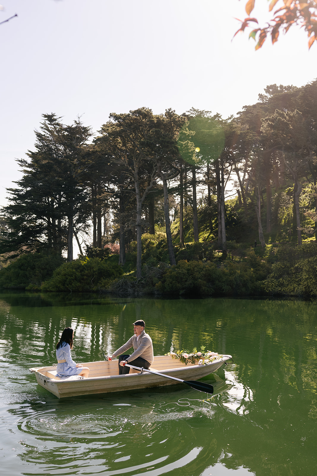 a couple taking engagement pictures on a rowboat in stow lake inside of golden gate park 