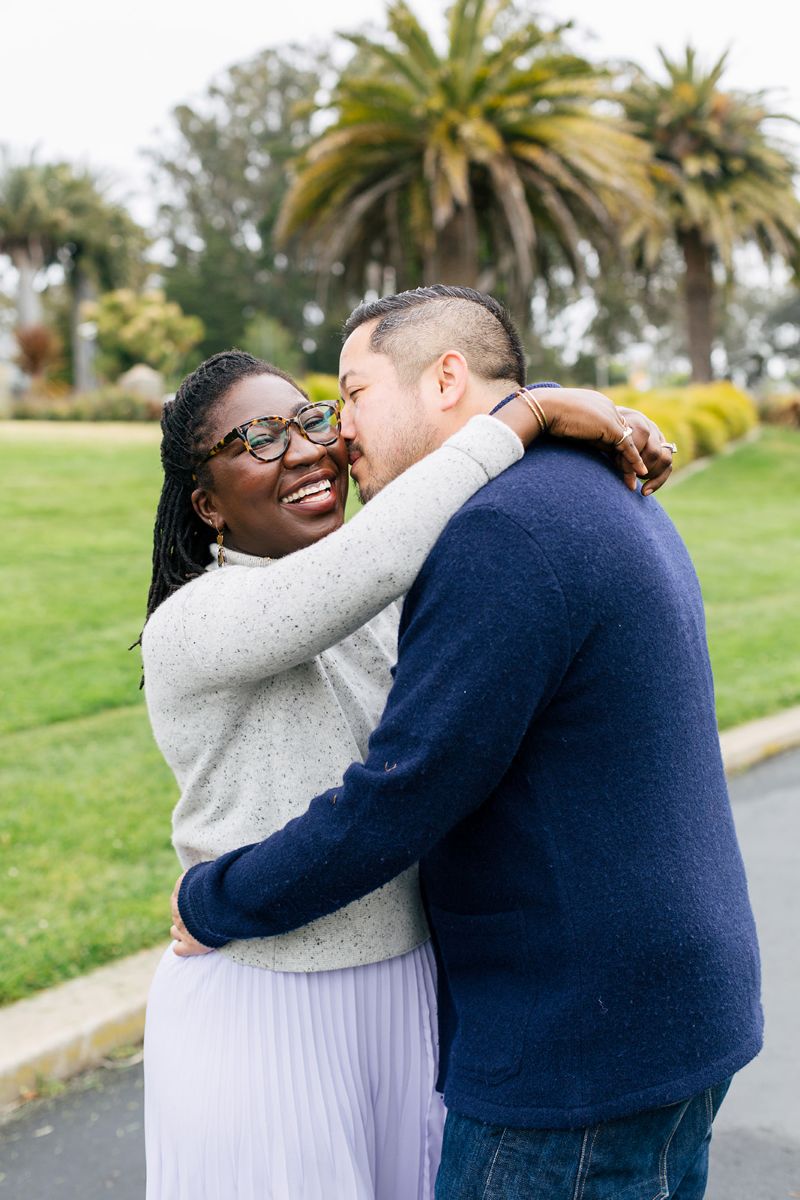 a man leaning in to kiss his partner and hugging her along a paved path at the music concourse in golden gate park 