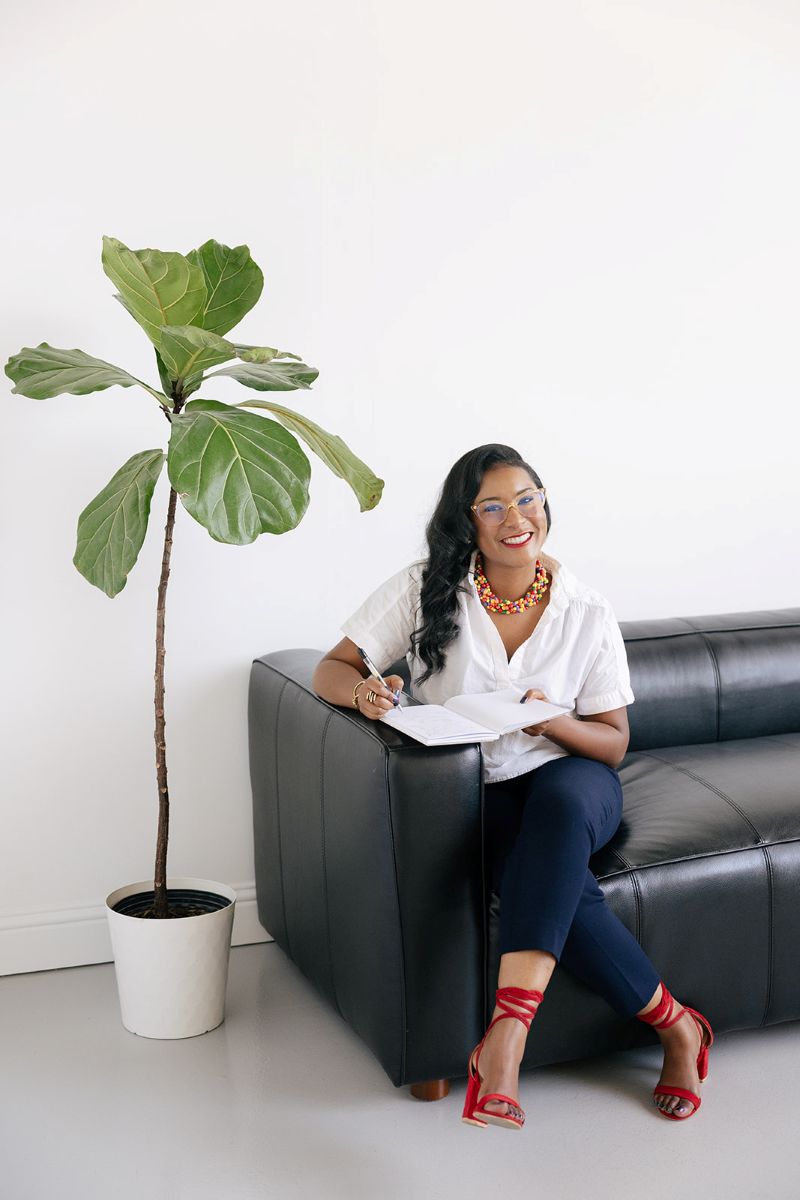 the owner of ebb and flow nutrition and consulting sitting on a black leather couch and writing in her notebook