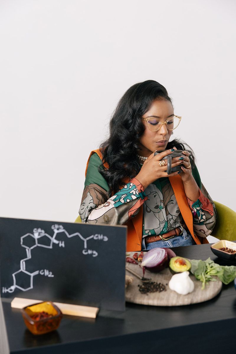 the owner of ebb and flow nutrition and consulting drinking from a mug in front of her are various vergetable and a diagram