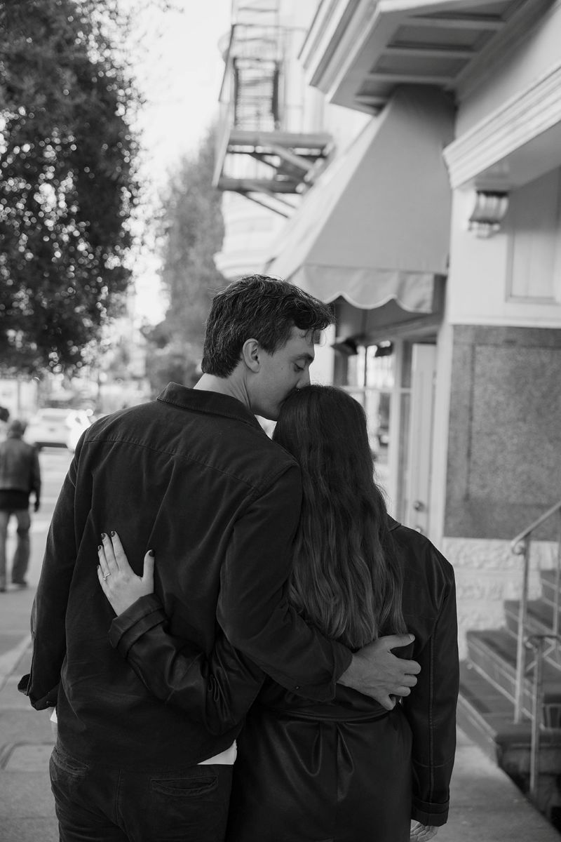 a man and woman walking down a street together with their arms around each other