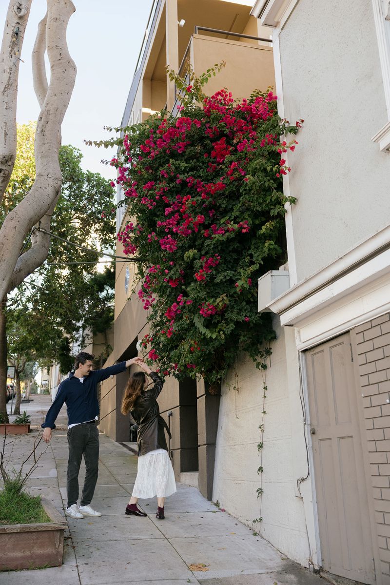 a man dancing with his partner on a street in north beach during their engagement session