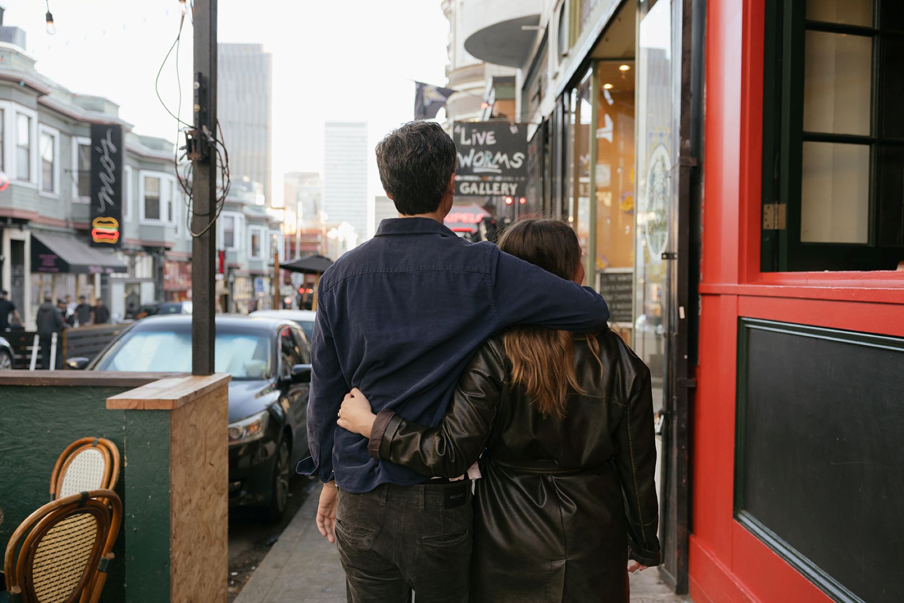 a couple walking with their arms around each other and wandering down a street in north beach