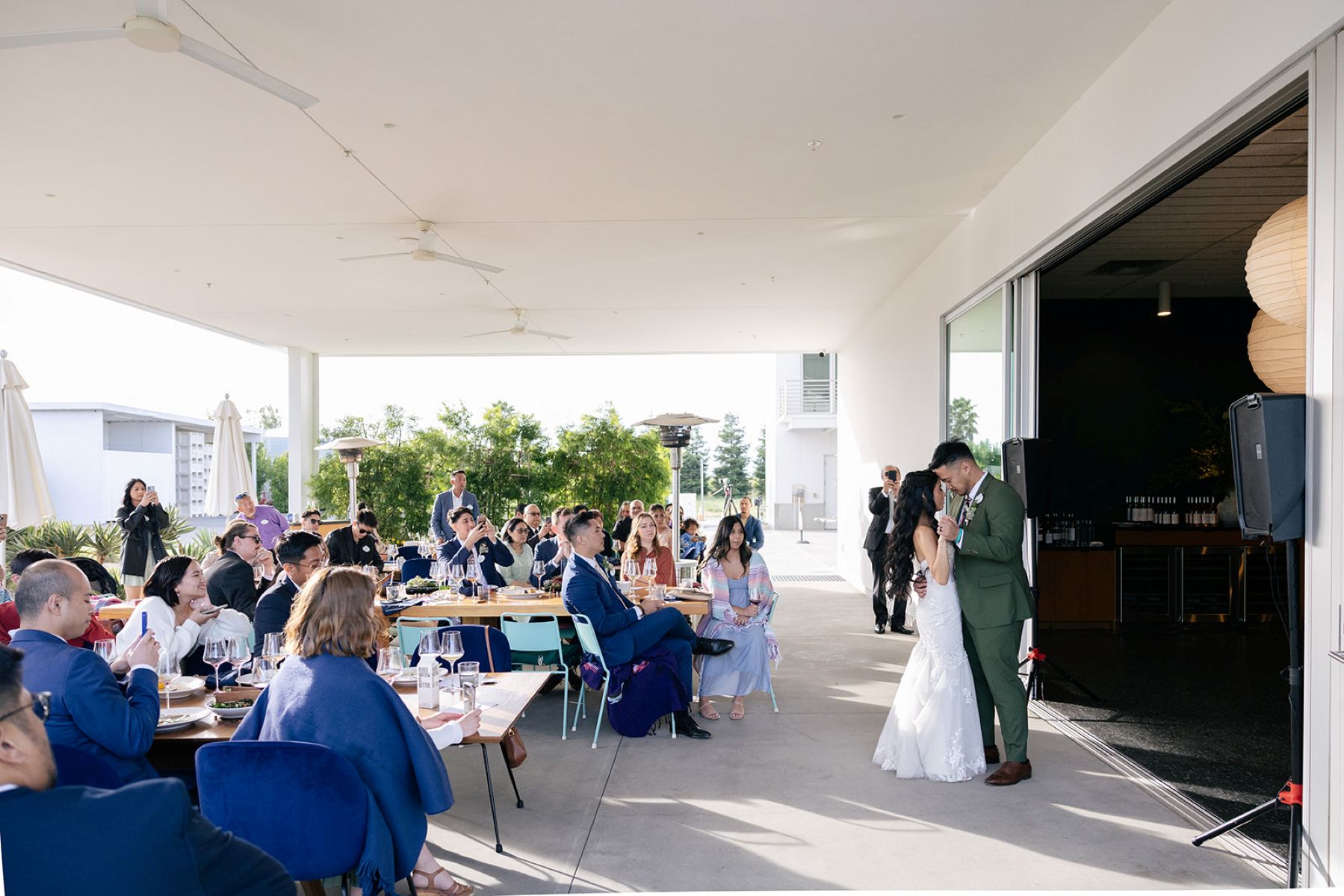 a couple sharing a first dance together at ashes and diamonds winery as their wedding guests watch 