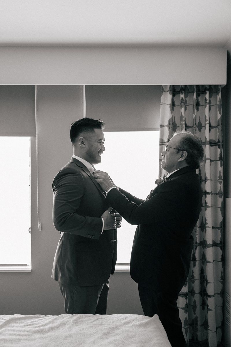 a father helpig his son put on his tux for his wedding 