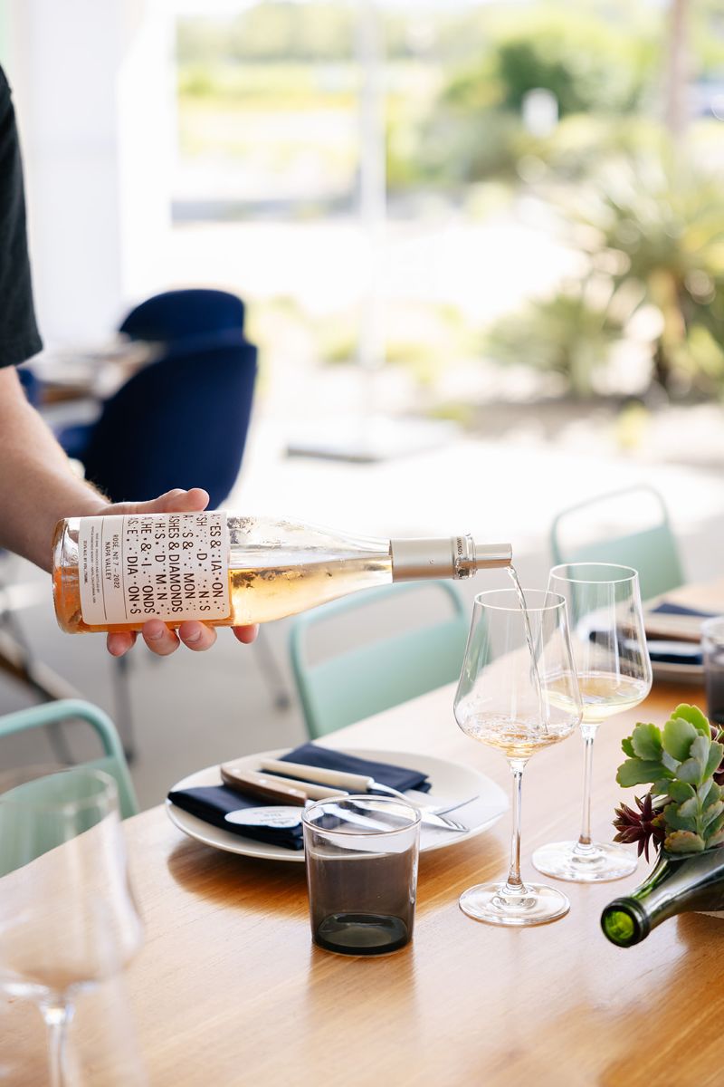 a server pouring a bottle of ashes and diamonds wine into a glass at a wedding reception 