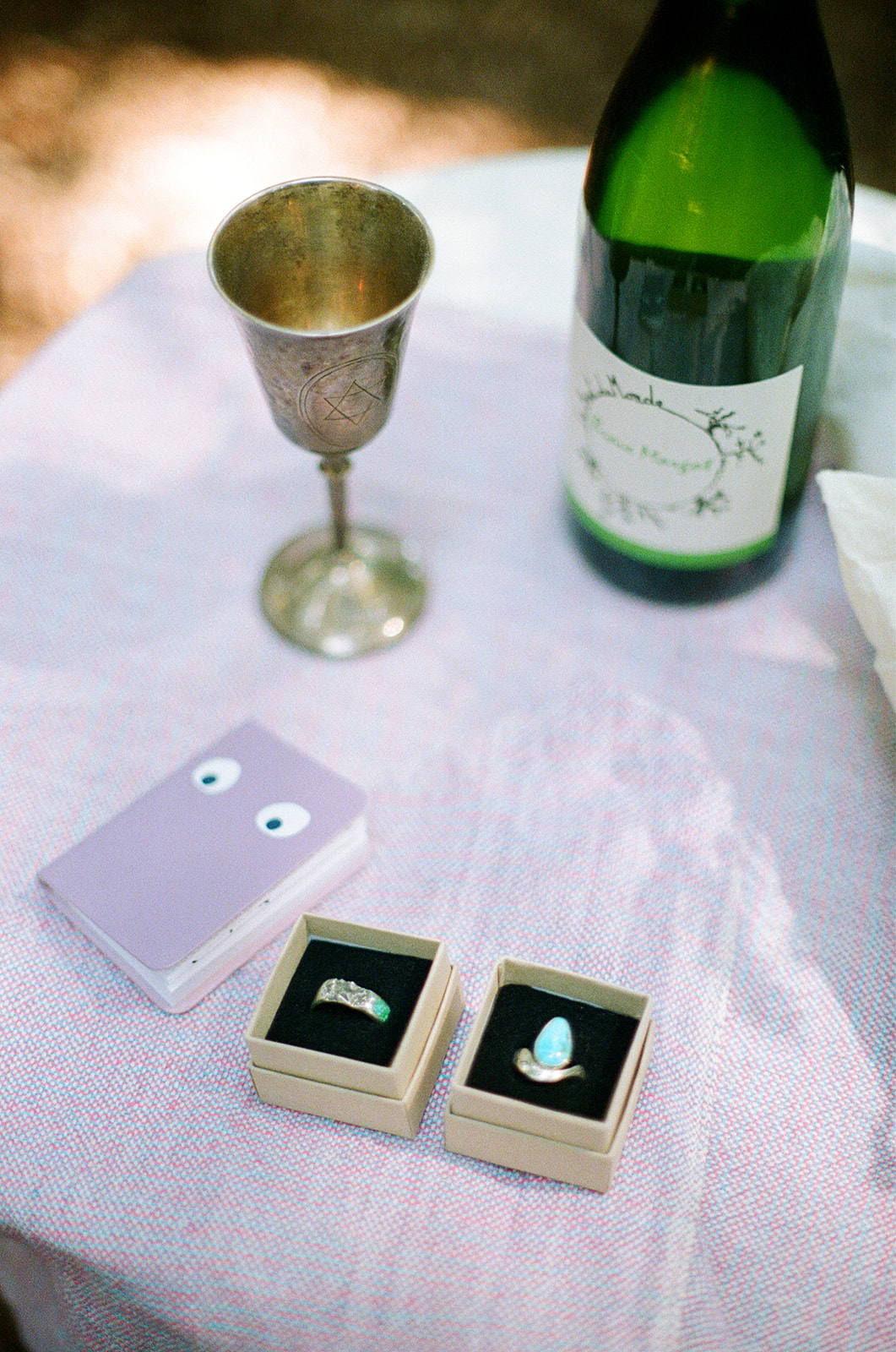 a film scan of rings in ring boxes, a notebook, a chalice, and a wine bottle 
