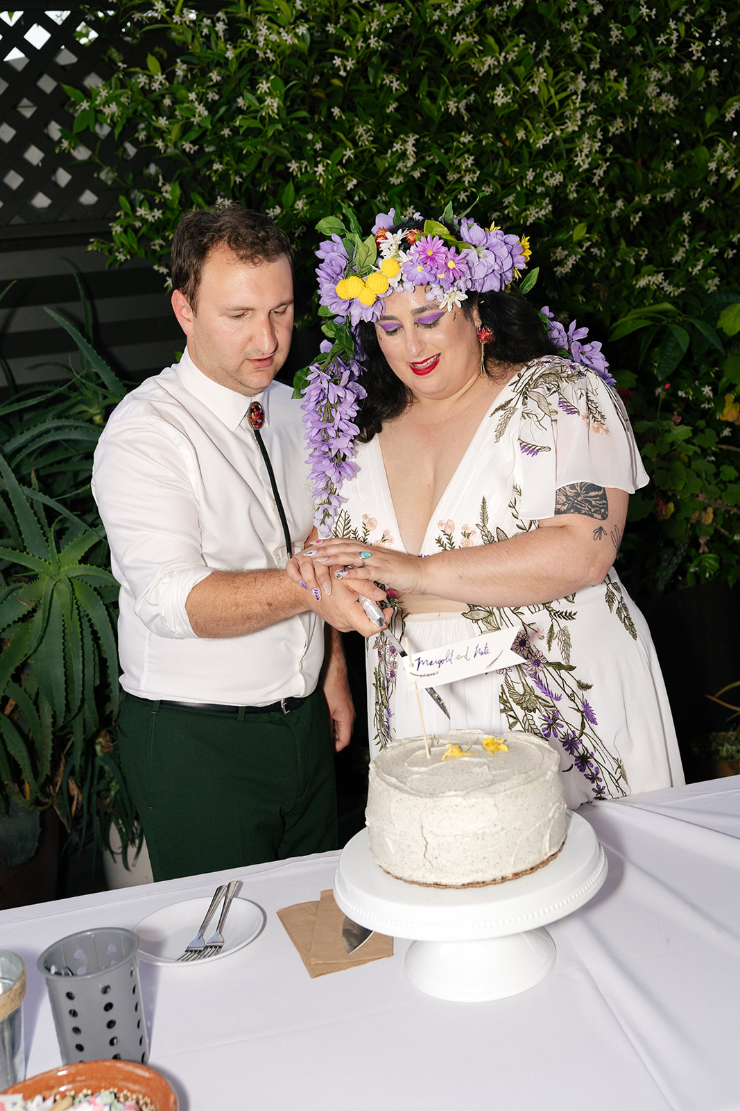 a couple cutting their wedding cake together at their wedding reception at nido's backyard 