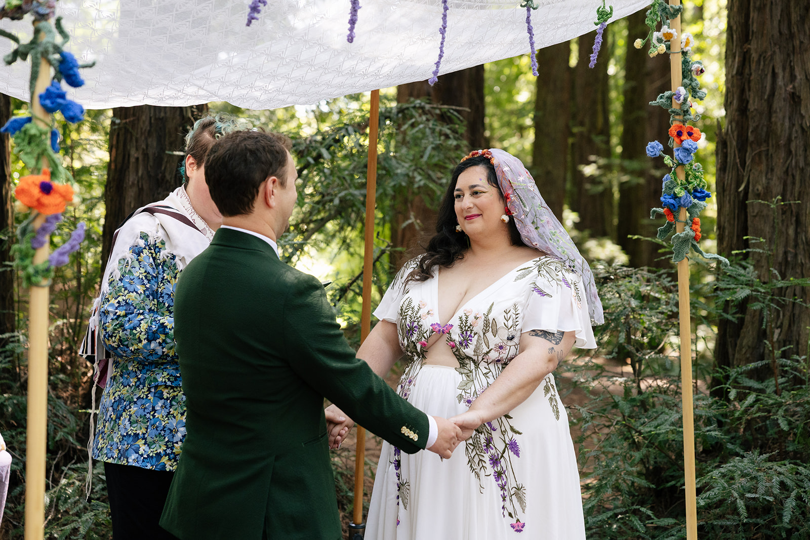 a couple holding hands under a chuppah during their wedding ceremony in roberts regional park 