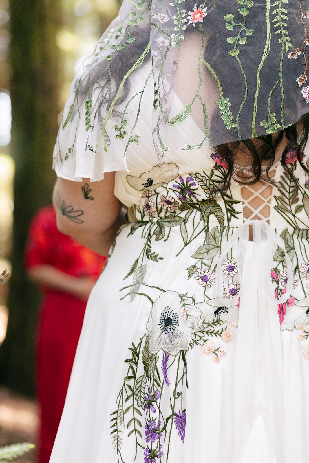 a bride wearing a white wedding dress with florals weaven into her dress and her veil 