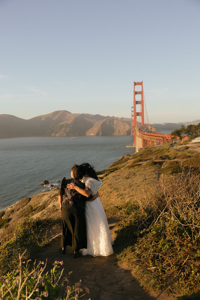 a wedding couple embraced while staring off into the ocean with a view of the golden gate bridge