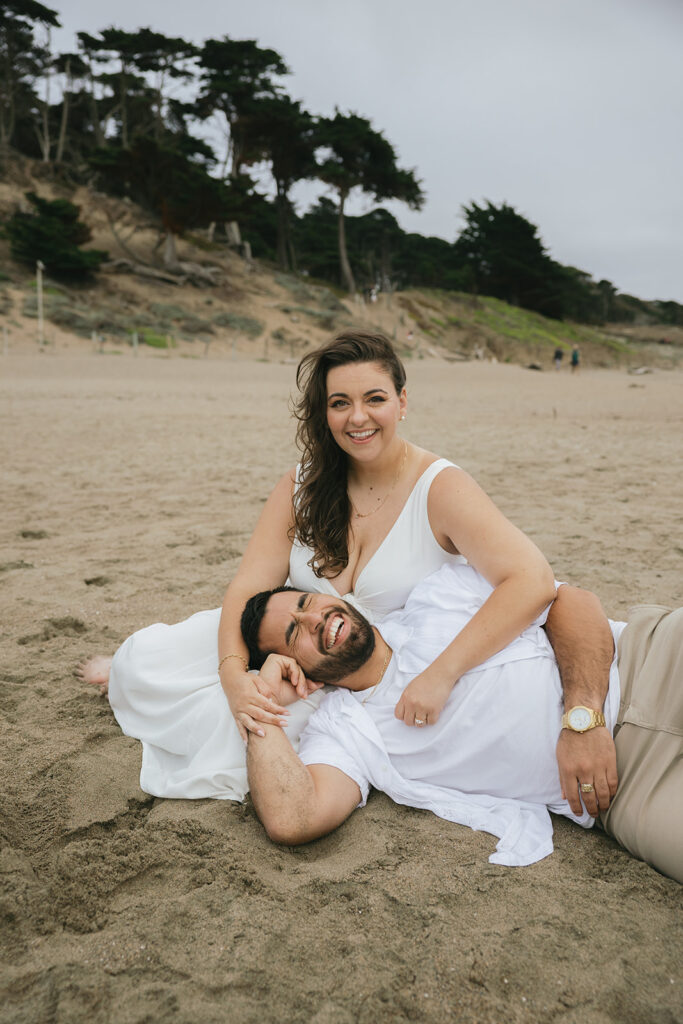 a couple laughing and sitting on the beach
