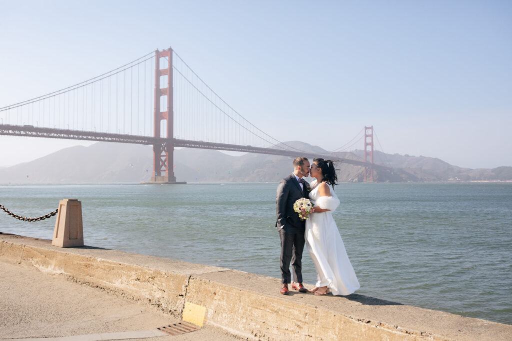 a wedding couple kissing in front of the golden gate bridge