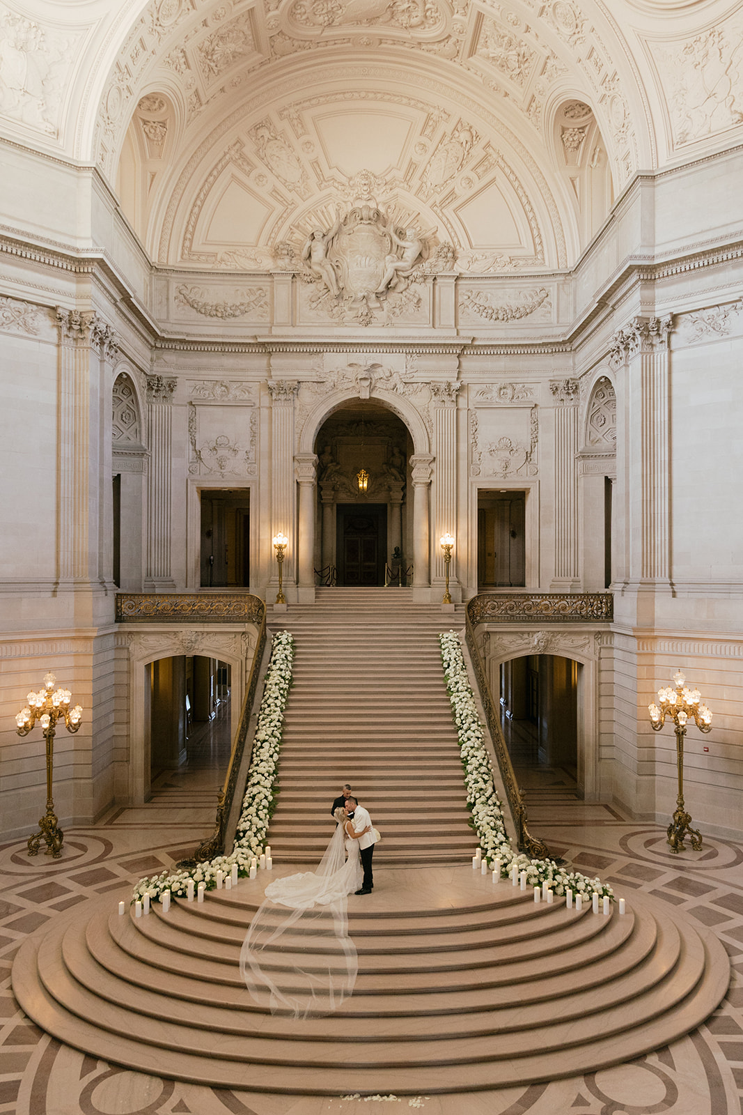 a couple kissing on the grand staircase inside of san francisco city hall during their wedding ceremony 