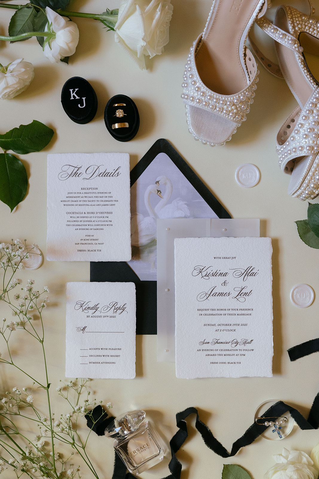 wedding detail photo including invitations, heels, perfume, rings, and black ribbon