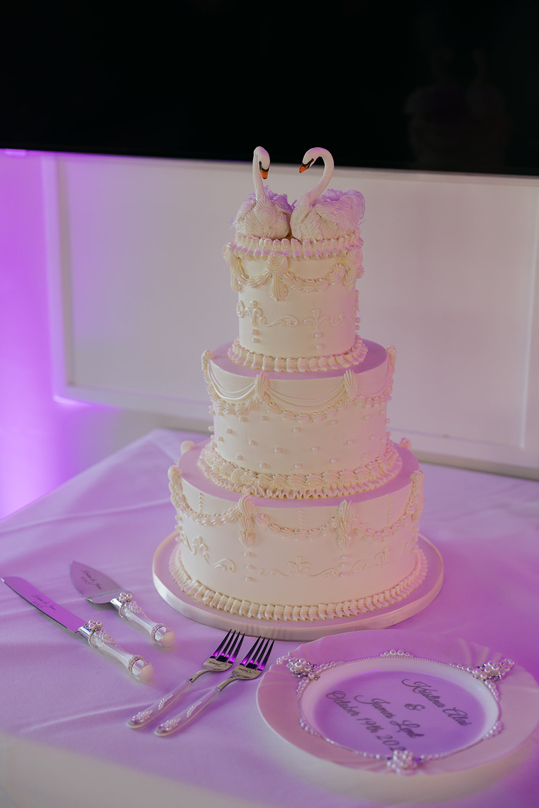 a white wedding cake with two swan cake toppers 