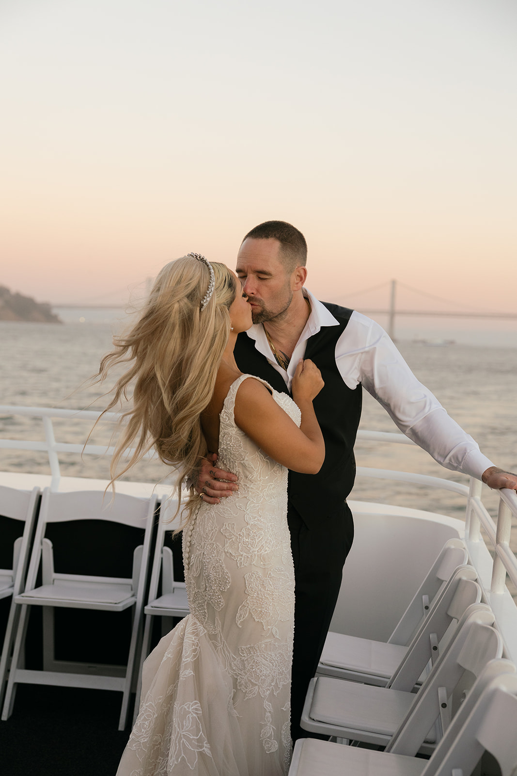 a couple kissing on a yacht during their wedding reception on the san francisco bay