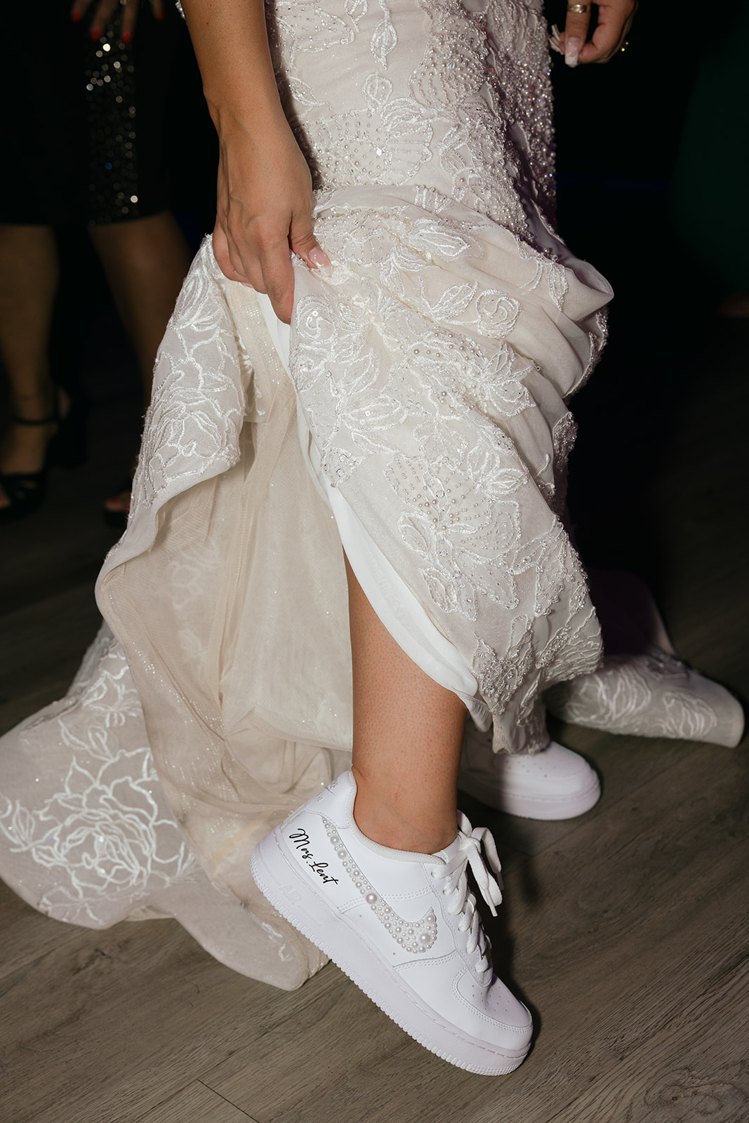 a bride showing off her embroided sneakers with her husband's last name 