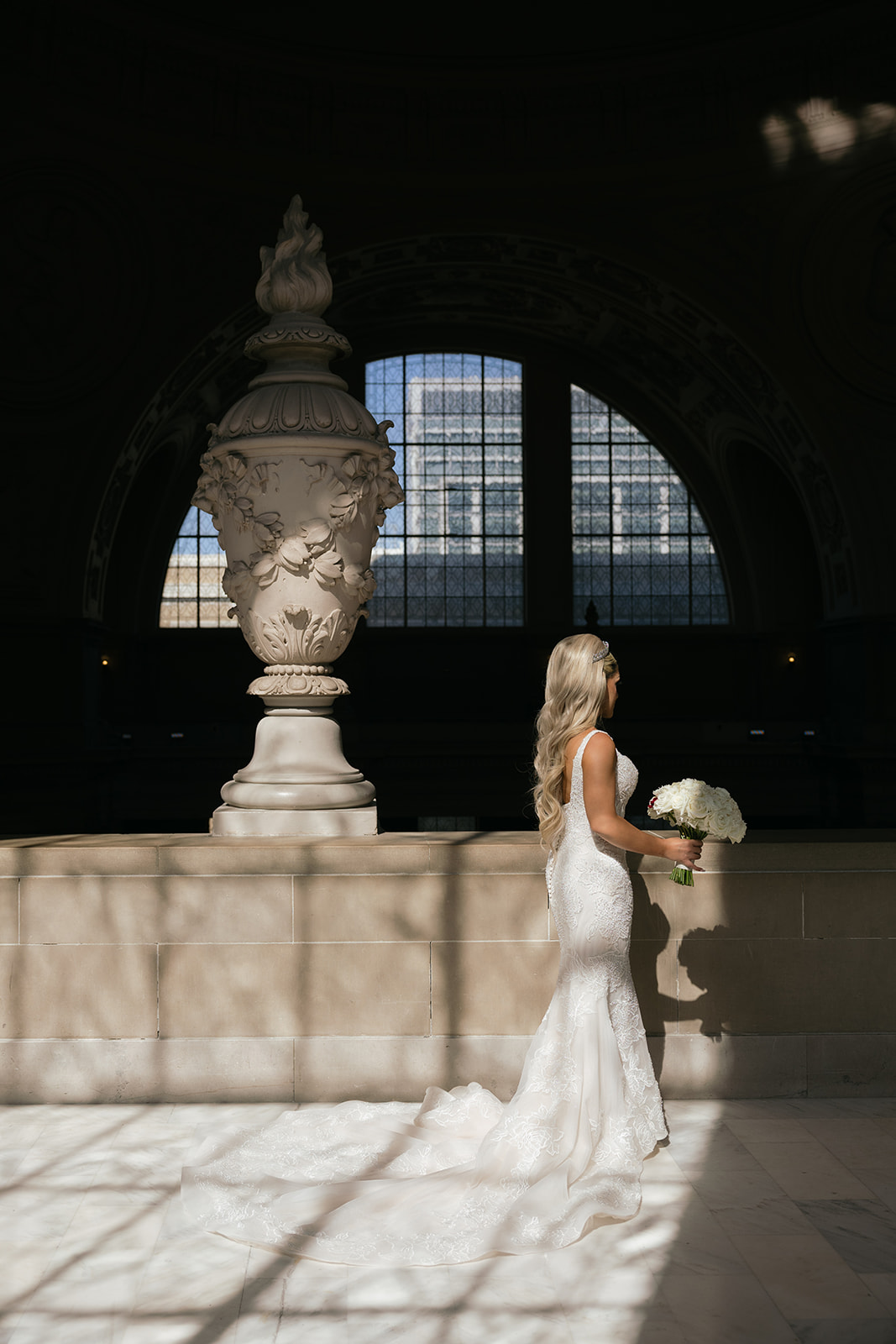 a bride holding a bouquet taking a wedding portrait inside san francisco city hall