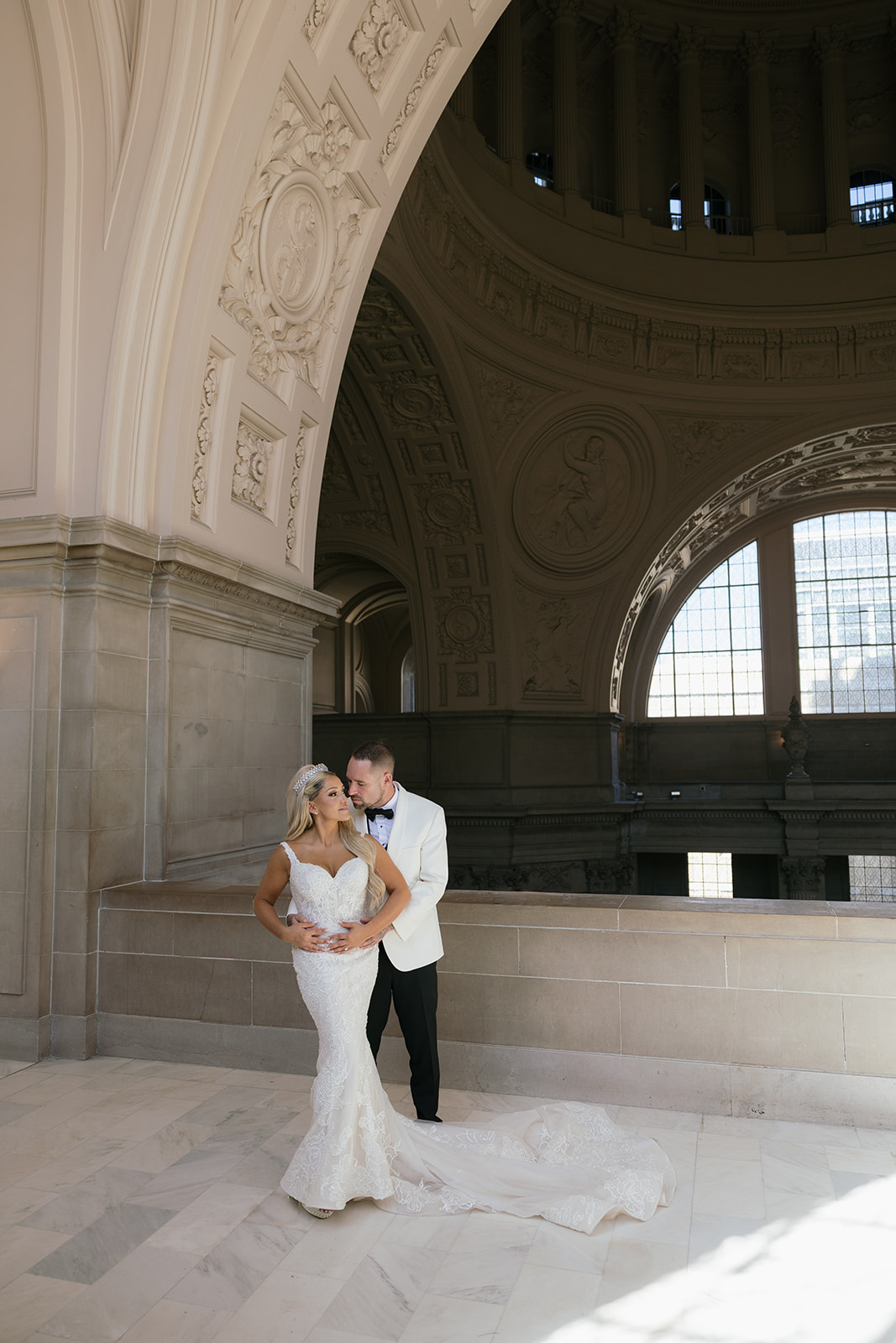 a couple on the mayor's balcony of san francisco city hall taking a couple's wedding portrait 